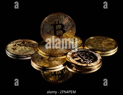 Monete d'oro closeup con logo bitcoin. Leader nella criptovaluta Bitcoin BTC su una cima di monete contro la superficie nera specchio. Un mucchio di decentralizzati Foto Stock
