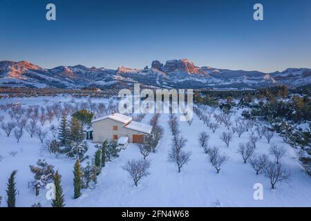 Vista aerea dei porti di Els / la catena montuosa di Los Puertos e dintorni del villaggio di Horta de Sant Joan in un tramonto invernale innevato (Tarragona, Spagna) Foto Stock