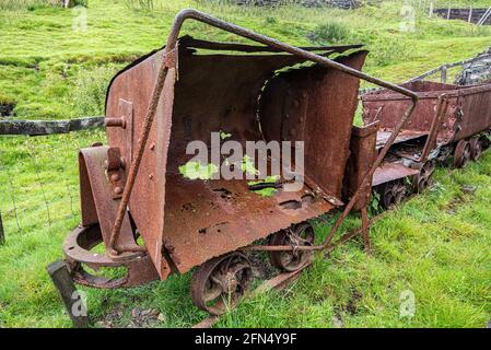 Vecchi camion minerari arrugginiscono all'ingresso di una vecchia miniera di piombo storica a Wanlockhead in Scozia. Foto Stock