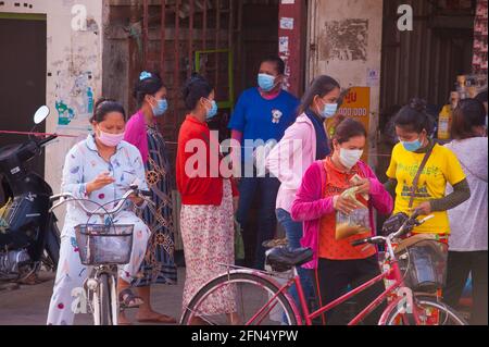 Phnom Penh, Cambogia. 14 maggio 2021. Dopo 4 settimane di blocco totale della città, il governo continua a dividere Phnom Penh in 3 zone colorate (rosso, arancione e giallo) a causa dell'aumento COVID - 19 in corso. Le lavoratrici cambogiane, alcune delle quali incinte, si allineano per acquistare prodotti alimentari da un piccolo negozio, che è stato cordonato fuori, in una 'Red zone', che significa alto rischio di infezione. Credit: Kraig Lieb / Alamy Live News Foto Stock