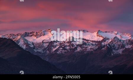 L'alba rossa sul massiccio innevato delle Maladetas e la vetta dell'Aneto. Vista dalla valle di Varradòs in autunno (Valle di Aran, Catalogna, Spagna) Foto Stock