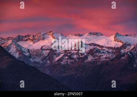 L'alba rossa sul massiccio innevato delle Maladetas e la vetta dell'Aneto. Vista dalla valle di Varradòs in autunno (Valle di Aran, Catalogna, Spagna) Foto Stock