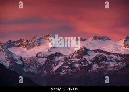 Alba rossastra sul massiccio innevato delle Maladetas e sulla vetta di Aneto. Vista dalla valle di Varradòs in autunno (Valle di Aran, Catalogna, Spagna) Foto Stock