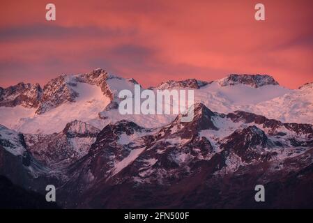 Alba rossastra sul massiccio innevato delle Maladetas e sulla vetta di Aneto. Vista dalla valle di Varradòs in autunno (Valle di Aran, Catalogna, Spagna) Foto Stock