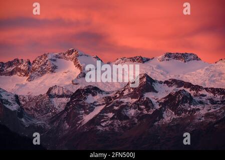 L'alba rossa sul massiccio innevato delle Maladetas e la vetta dell'Aneto. Vista dalla valle di Varradòs in autunno (Valle di Aran, Catalogna, Spagna) Foto Stock