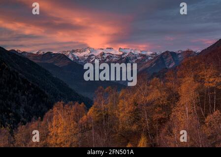 L'alba rossa sul massiccio innevato delle Maladetas e la vetta dell'Aneto. Vista dalla valle di Varradòs in autunno (Valle di Aran, Catalogna, Spagna) Foto Stock