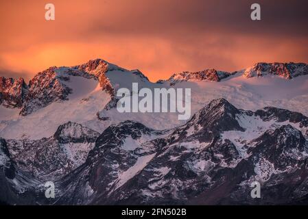 Alba rossastra sul massiccio innevato delle Maladetas e sulla vetta di Aneto. Vista dalla valle di Varradòs in autunno (Valle di Aran, Catalogna, Spagna) Foto Stock