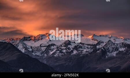 Alba rossastra sul massiccio innevato delle Maladetas e sulla vetta di Aneto. Vista dalla valle di Varradòs in autunno (Valle di Aran, Catalogna, Spagna) Foto Stock