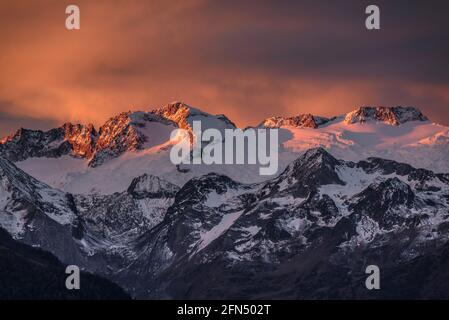 L'alba rossa sul massiccio innevato delle Maladetas e la vetta dell'Aneto. Vista dalla valle di Varradòs in autunno (Valle di Aran, Catalogna, Spagna) Foto Stock