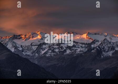 Alba rossastra sul massiccio innevato delle Maladetas e sulla vetta di Aneto. Vista dalla valle di Varradòs in autunno (Valle di Aran, Catalogna, Spagna) Foto Stock