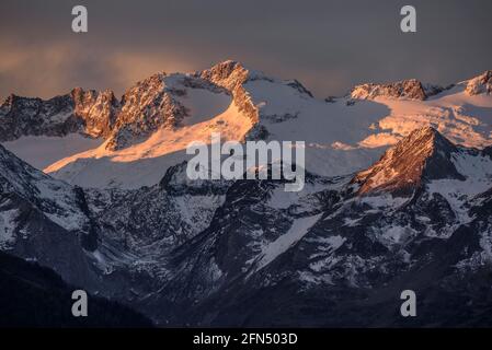 L'alba rossa sul massiccio innevato delle Maladetas e la vetta dell'Aneto. Vista dalla valle di Varradòs in autunno (Valle di Aran, Catalogna, Spagna) Foto Stock