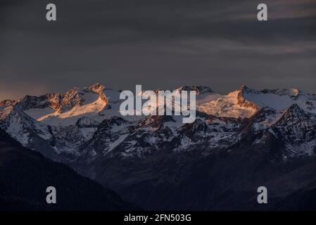 Alba rossastra sul massiccio innevato delle Maladetas e sulla vetta di Aneto. Vista dalla valle di Varradòs in autunno (Valle di Aran, Catalogna, Spagna) Foto Stock