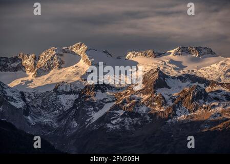 L'alba rossa sul massiccio innevato delle Maladetas e la vetta dell'Aneto. Vista dalla valle di Varradòs in autunno (Valle di Aran, Catalogna, Spagna) Foto Stock