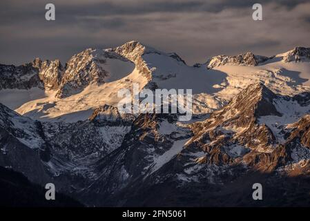 Alba rossastra sul massiccio innevato delle Maladetas e sulla vetta di Aneto. Vista dalla valle di Varradòs in autunno (Valle di Aran, Catalogna, Spagna) Foto Stock