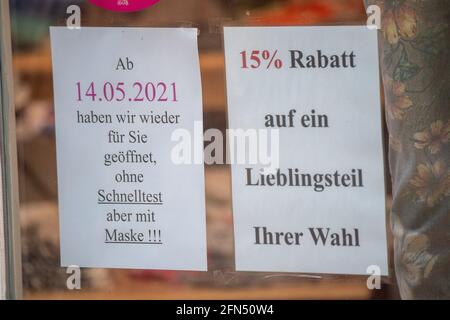 Stralsund, Germania. 14 maggio 2021. Un segno con il testo 'dal 14.05.2021 siamo aperti di nuovo per voi senza test rapido ma con maschera!!!' Pende su una finestra di un negozio nel centro storico di Stralsund. Retail nel distretto di Vorpommern-Rügen riapre, è il primo distretto di Meclemburgo-Pomerania occidentale, in cui i negozi sono autorizzati ad aprire completamente di nuovo, perché l'incidenza di sette giorni vi è già al di sotto di 50. Credit: Stefan Sauer/dpa/Alamy Live News Foto Stock