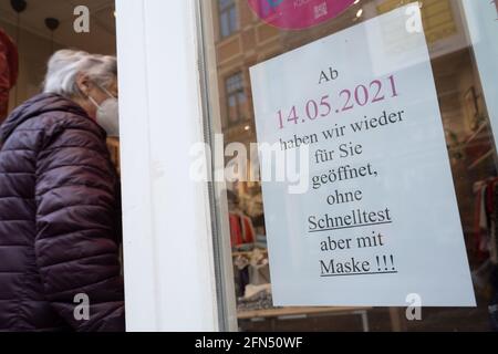 Stralsund, Germania. 14 maggio 2021. Un segno con il testo 'dal 14.05.2021 siamo aperti di nuovo per voi senza test rapido ma con maschera!!!' Pende su una finestra di un negozio nel centro storico di Stralsund. Retail nel distretto di Vorpommern-Rügen riapre, è il primo distretto di Meclemburgo-Pomerania occidentale, in cui i negozi sono autorizzati ad aprire completamente di nuovo, perché l'incidenza di sette giorni vi è già al di sotto di 50. Credit: Stefan Sauer/dpa/Alamy Live News Foto Stock