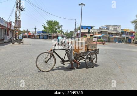 Beawar, Rajasthan, India, 13,2021 maggio: Il lavoratore indiano spinge un carrello a tre cicli carico di beni di consumo in un mercato desertato durante il blocco COVID-19 in corso a Beawar. Credit: Sumit Saraswat/Alamy Live News Foto Stock