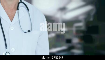 Composizione della sezione centrale del medico maschile in camice di laboratorio con stetoscopio oltre l'ospedale fuori fuoco Foto Stock