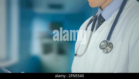 Composizione della sezione centrale del medico maschile in camice di laboratorio con stetoscopio oltre l'ospedale fuori fuoco Foto Stock