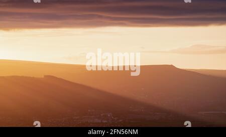 I suggestivi fasci di luce illuminano la Valle dell'Aire mentre il sole tramontante scende sotto una bruscante riva di nuvole. Il pinnacolo di Wainman è visibile all'orizzonte. Foto Stock