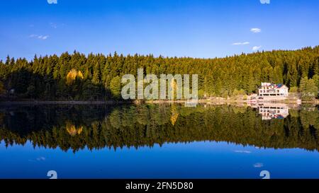 Un'affascinante foto panoramica di un paesaggio che cattura Artvin Savsat in Turchia. Il lago limpido vicino ad un sentiero che ha un edificio bianco di fronte ad un Foto Stock