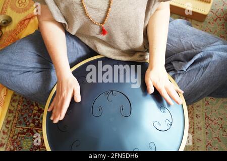 Donna con sta suonando un tamburo RAV, primo piano di mani woman che suonano impani tamburo, strumento musicale per la guarigione del suono.Donna sta suonando un tamburo RAV Foto Stock