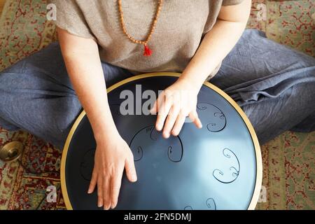 Donna con sta suonando un tamburo RAV, primo piano di mani woman che suonano impani tamburo, strumento musicale per la guarigione del suono.Donna sta suonando un tamburo RAV Foto Stock