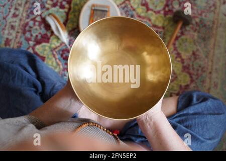 Donna caucasica che tiene in mano una ciotola tibetana per una sana terapia di guarigione Foto Stock