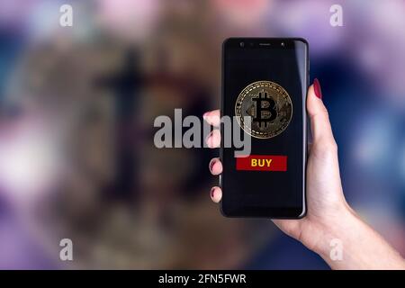 Smartphone con simbolo Bitcoin e icona 'buy' - criptovaluta commerciale concetto Foto Stock