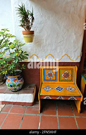 Patio coloniale spagnolo con una sedia in legno rustica dipinta a mano e una pentola di argilla smaltata artigianale su un pavimento in piastrelle di terracotta a San Diego California. Foto Stock