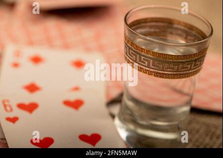 Carte da gioco e un bicchiere di vodka su un tavolo coperto di burlap grossolano. Primo piano, messa a fuoco selettiva. Foto Stock