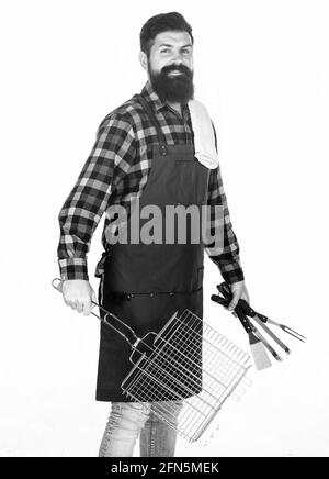 Consigli per cucinare la carne. Stagione barbecue. Hipster con bearded indossare grembiule per barbecue. Tostatura e grigliatura degli alimenti. Uomo tenere utensili da cucina barbecue. Strumenti Foto Stock