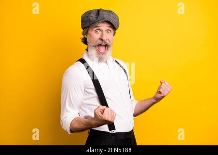 Foto di un uomo anziano eccitato felice positivo sorriso gioia vincere vittoria pugni mano isolato su sfondo giallo Foto Stock