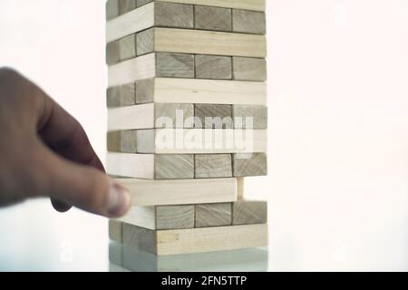 La torre da blocchi di legno e di mano d'uomo prendere un blocco Foto Stock