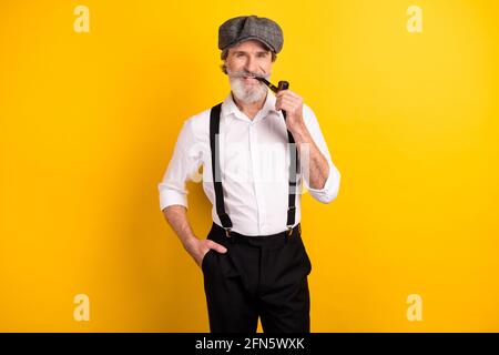 Ritratto fotografico di senior gentleman in vintage vestiti fumo tabacco tubo di legno sorridente isolato giallo luminoso sfondo Foto Stock