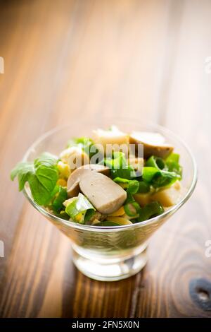 insalata fresca di dieta primaverile di funghi, uova, cipolle verdi su un tavolo di legno Foto Stock