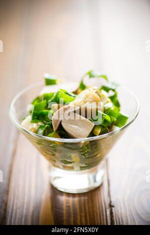 insalata fresca di dieta primaverile di funghi, uova, cipolle verdi su un tavolo di legno Foto Stock