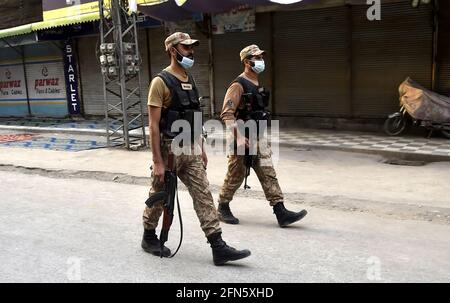 Peshawar. 14 maggio 2021. Soldati pakistani pattugliano in un mercato nel Peshawar del Pakistan nord-occidentale il 14 maggio 2021. Secondo il National Command and Operation Center (NCOC), che sovrintende alla risposta del paese alla pandemia, tutte le aziende, gli hotel, i parchi, i luoghi ricreativi e i centri commerciali rimarranno chiusi dall'8 al 16 maggio, coprendo le vacanze Eid al-Fitr dal 10 al 15 maggio in Pakistan. Credit: Saeed Ahmad/Xinhua/Alamy Live News Foto Stock