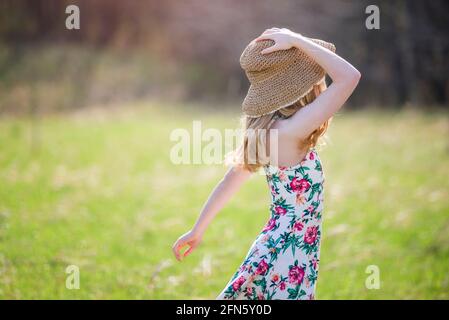 Bella ragazza bionda teen all'aperto in spoglietta e cappello da sole, retroilluminata. Foto Stock