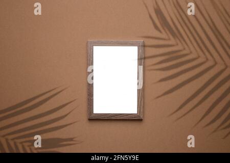 Quadro vuoto su sfondo marrone tendenza con luce ombra piante tropicali come modello per la promozione di eventi, presentazione di design, portafoglio di sé ecc. Foto Stock