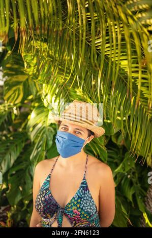 Giovane uomo con maschera medica in clima tropicale, nuovo concetto normale. Foto Stock