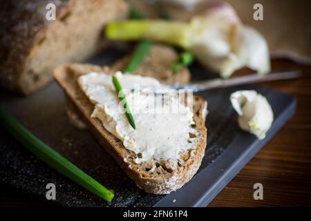 Pane di grano saraceno fatto in casa con formaggio all'aglio spalmato su un legno tabella Foto Stock