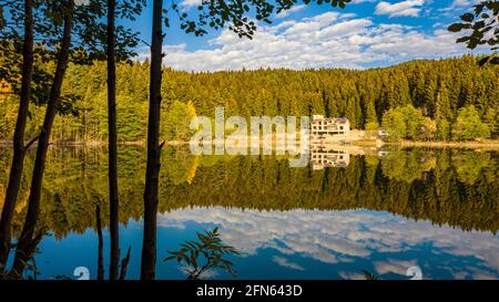 Un'affascinante foto panoramica di un paesaggio che cattura Artvin Savsat in Turchia. Il lago limpido vicino ad un sentiero che ha un edificio bianco di fronte ad un Foto Stock