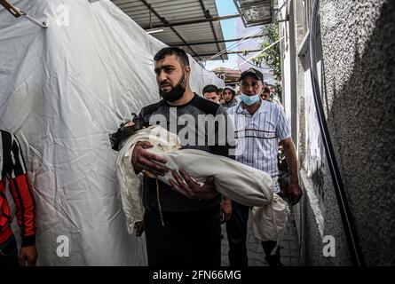 Gaza, Palestina. 14 maggio 2021. (NOTA DELLA REDAZIONE: Immagine della morte) il palestinese porta il corpo di un bambino, Ibrahim al-Rantisi, ucciso durante un attacco aereo israeliano, prima della sua sepoltura a Rafah, nella striscia di Gaza meridionale. Credit: SOPA Images Limited/Alamy Live News Foto Stock