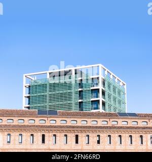 Contrasto di un edificio moderno dietro un vecchio edificio in pietra a Valencia, Spagna, con cielo blu e spazio per le copie. Concetto di architettura Foto Stock