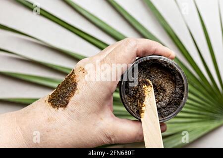 In una mano di donna è un vaso con un scrub corpo fatto da ingredienti naturali. Cosmetici fatti a mano. Home spa Foto Stock