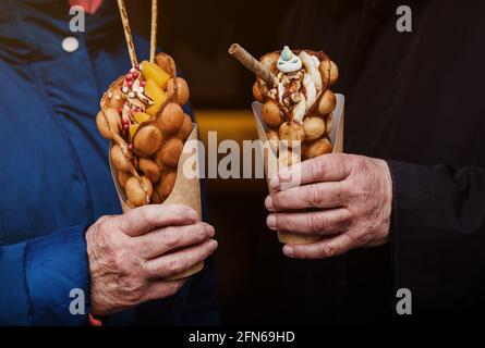 accoppia le mani con deliziosi waffle a bolle d'aria. Foto Stock