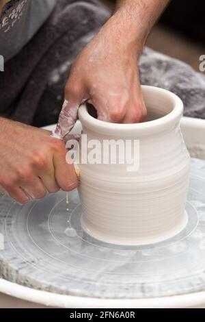 Potter / vasai mani abilmente mano gettando una ceramica gettato vaso di argilla su una ruota di rotazione. Inghilterra. UK (123) Foto Stock