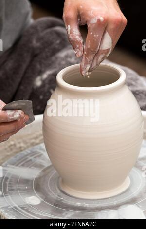 Potter / vasai mani abilmente mano gettando una ceramica gettato vaso di argilla su una ruota di rotazione. Inghilterra. UK (123) Foto Stock