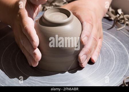 Le mani dei vasai si sentono abilmente la base dopo aver girato e lanciato una mano di ceramica gettato vaso di argilla su una ruota di rotazione. Inghilterra. UK (123) Foto Stock